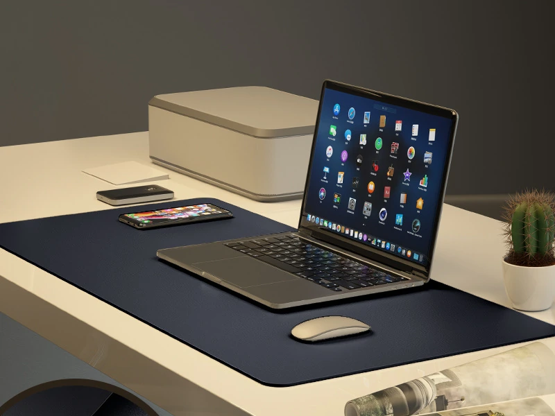 Black desk mat with a laptop and mouse; electronics are styling props